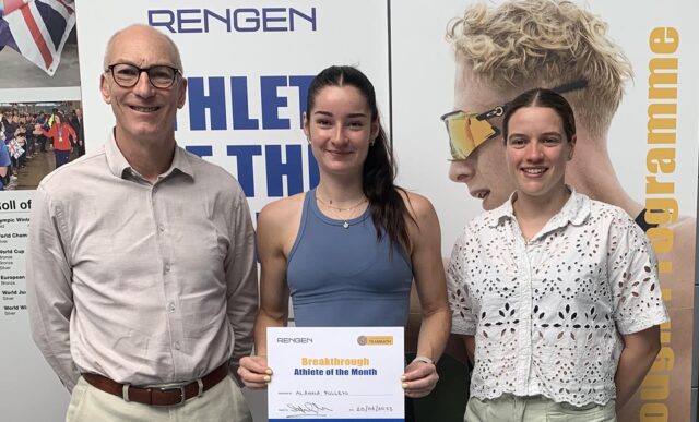 A picture of Alanna Pullen, the Team Bath Rengen Athlete of the Month for May 2025, holding a certificate in front of a display board. She is flanked by University of Bath Director of Sport Stephen Baddeley (left) and Performance Sport Officer Sarah Collin.