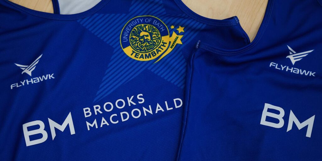 A close of blue netball kit featuring the Team Bath Netball, Flyhawk and Brooks Macdonald logos.