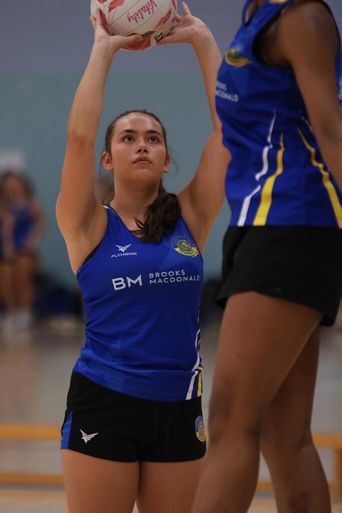 A netball wearing blue Team Bath kit lines up a shot