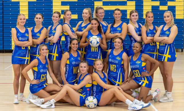 The Team Bath Netball 2026 NXT Gen League squad. 10 players are standing with their arms crossed, Sienna Rutherford is in the middle holding a ball, and 6 players are sitting or kneeling at the front.