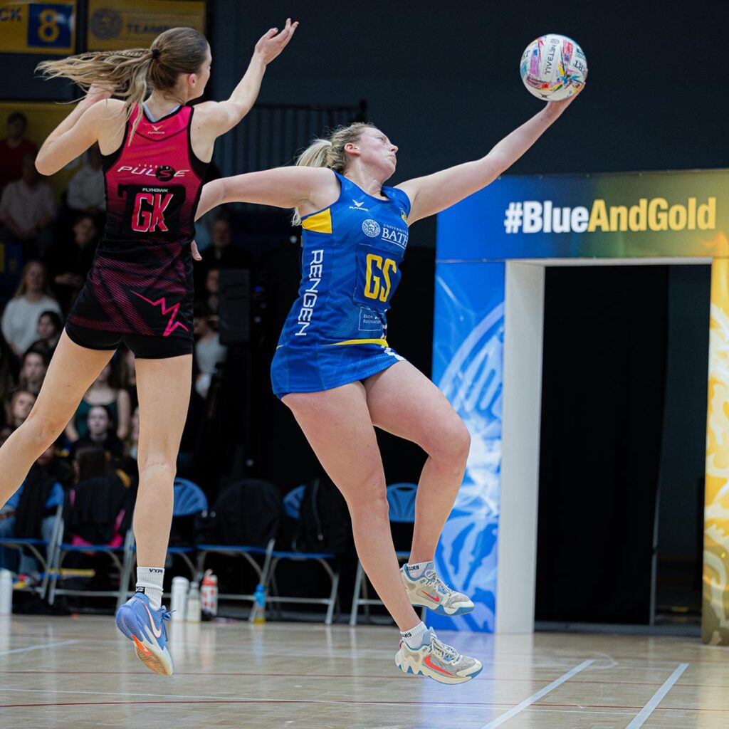 Team Bath Netball shooter Lucy Herdman catches the ball at full stretch with her left hand, feet off the ground