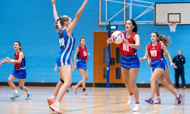 Netball players on court in a school sports hall