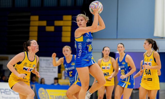 Team Bath Netball's Lowri Windsor leaping to catch the ball and turning to look down the court