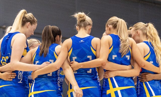 Team Bath Netball players huddle with their arms around each other's backs before a match